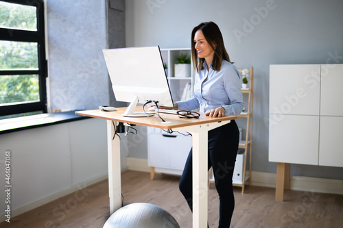 Woman Using Adjustable Height Standing Desk In Office photo