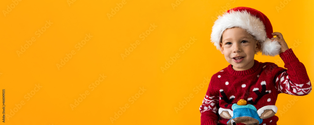 Portrait of happy smiling positive joyful positive preschool little boy in red warm santa hat showing thumb up on orange, yellow background. Winter, holiday, celebration, Christmas, New Year copy Portrait of happy smiling positive joyful positive preschool little boy in red warm santa hat showing thumb up on orange, yellow background. Winter, holiday, celebration, Christmas, New Year copy
