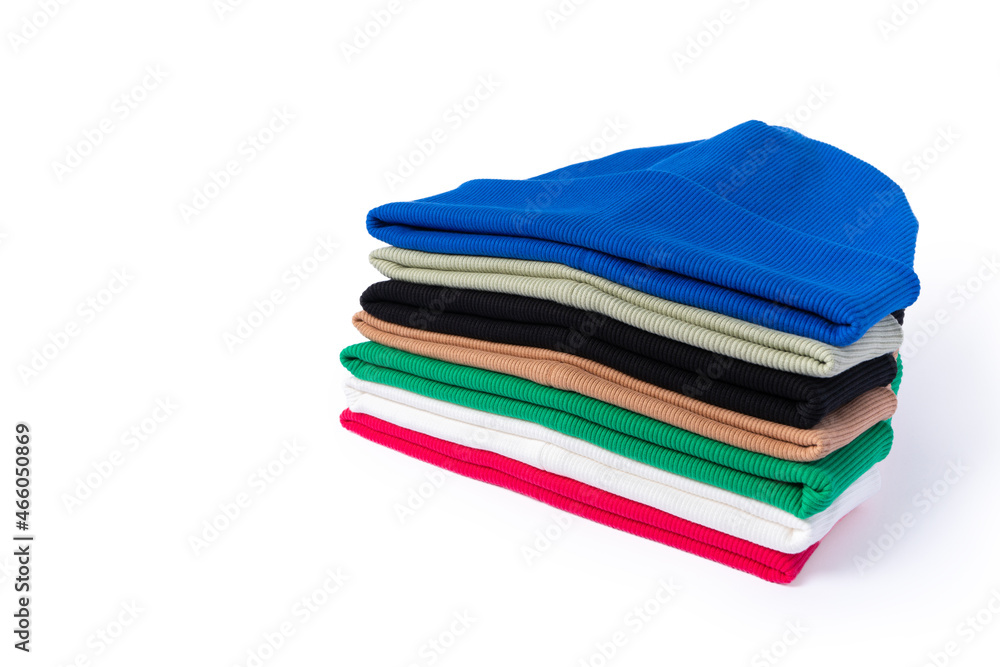 Warming stylish handmade beanie hats in different colors stacked in a stack on a white background with a place for text. Warming stylish handmade beanie hats in different colors stacked in a stack on a white background with a place for text.