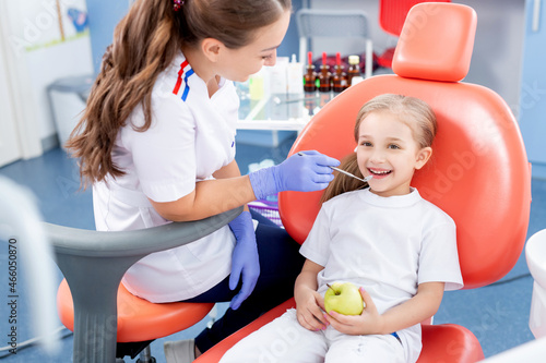 pediatric dentist checks caries in a little girl. beautiful girl is smiling in dentist's office. concept is a children's medical examination.