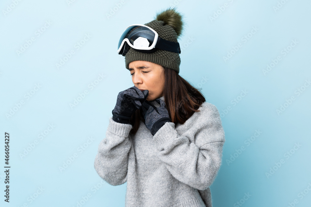 Mixed race skier girl with snowboarding glasses over isolated blue background coughing a lot. Mixed race skier girl with snowboarding glasses over isolated blue background coughing a lot.