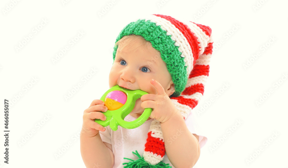 Portrait of baby in knitted gnome winter hat biting rattle toy on a white background Portrait of baby in knitted gnome winter hat biting rattle toy on a white background
