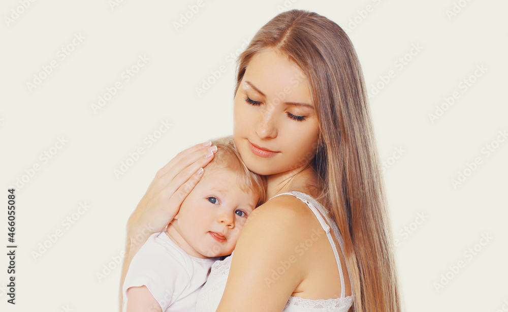 Portrait of beautiful young mother hugging and soothes her baby on a white background Portrait of beautiful young mother hugging and soothes her baby on a white background