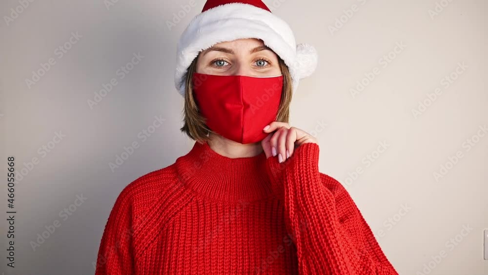 woman in santa claus hat and red sweater pointing at importance of wearing mask. Covid christmas concept woman in santa claus hat and red sweater pointing at importance of wearing mask. Covid christmas concept