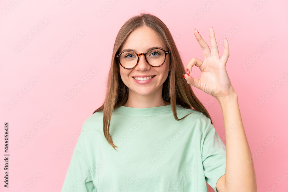 Young Lithuanian woman isolated on pink background With glasses and doing OK sign Young Lithuanian woman isolated on pink background With glasses and doing OK sign