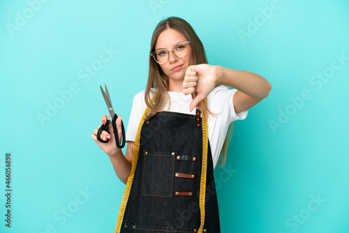 Young Lithuanian seamstress woman isolated on blue background showing thumb down with negative expression © luismolinero