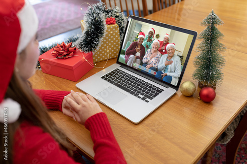 Caucasian woman in santa hat making christmas laptop video call with smiling diverse senior friends