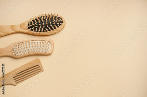 three different wooden combs on a beige background with space for text