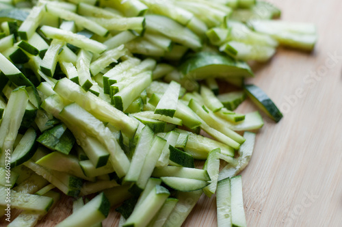 Finely sliced fresh cucumbers on a wooden cutting board with blurred edges