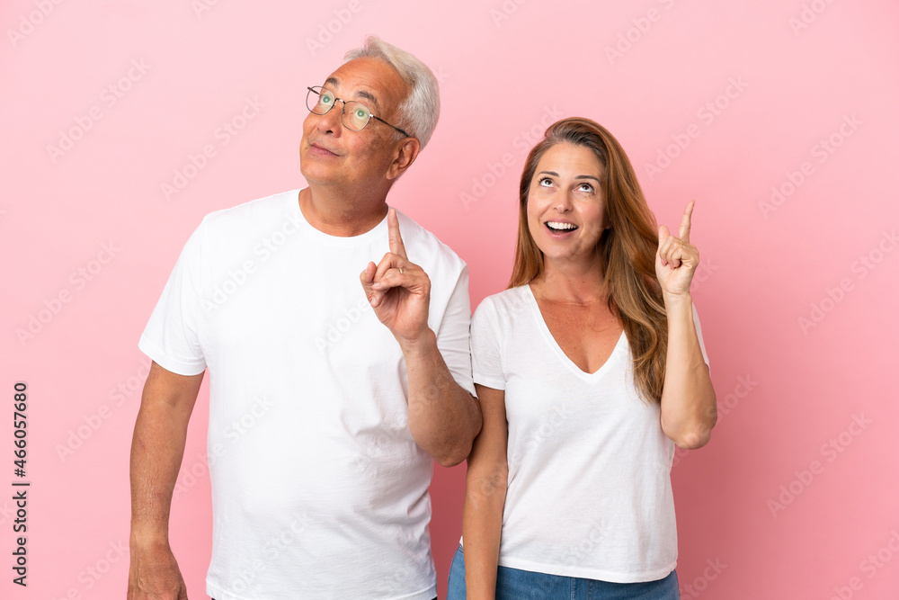 Middle age couple isolated on pink background thinking an idea pointing the finger up Middle age couple isolated on pink background thinking an idea pointing the finger up