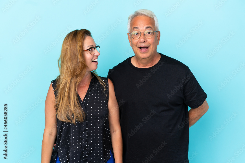 Middle age couple isolated on blue background with surprise facial expression Middle age couple isolated on blue background with surprise facial expression