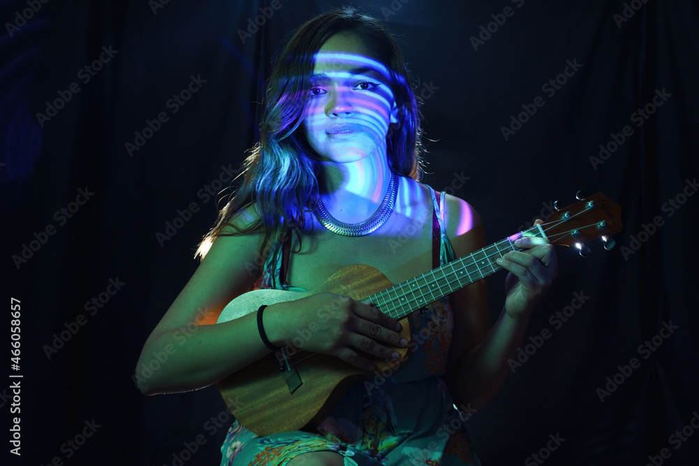A woman in a black dress is learning to play the ukulele with visual effects A woman in a black dress is learning to play the ukulele with visual effects
