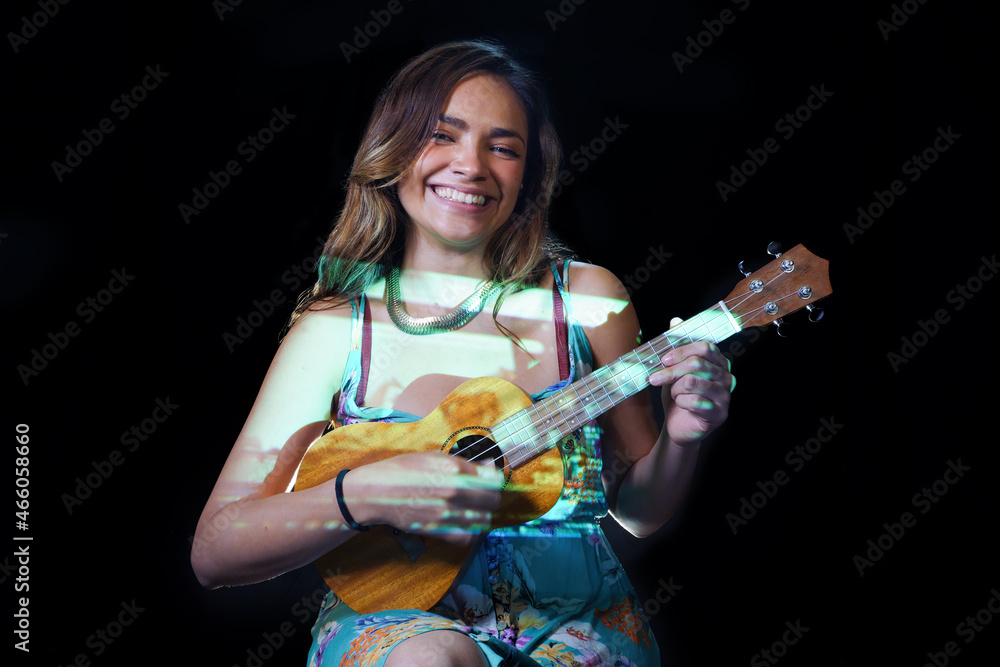 Portrait a woman playing the ukulele isolate on black background. Free from copy space