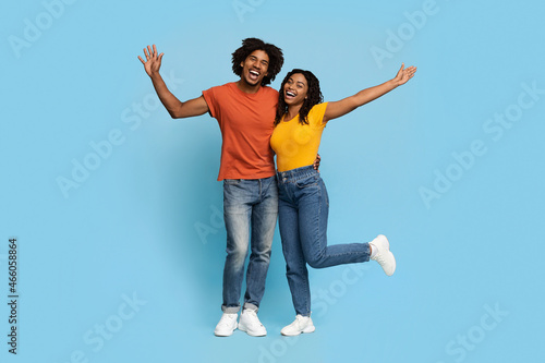 Happy african american lovers embracing over blue studio background