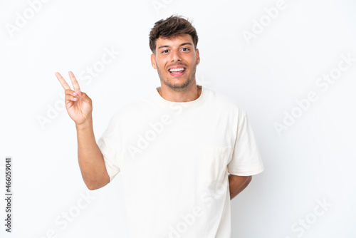 Young caucasian handsome man isolated on white background smiling and showing victory sign