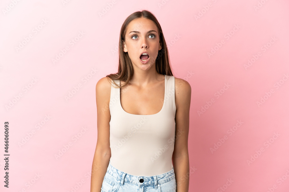 Obraz premium Young woman over isolated pink background looking up and with surprised expression
