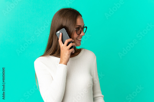 Young woman over isolated blue background keeping a conversation with the mobile phone with someone