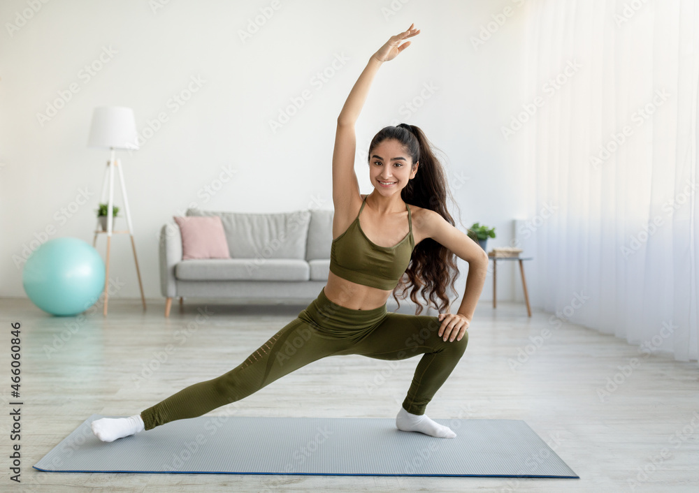 Sporty Indian woman stretching her body during home workout, copy space