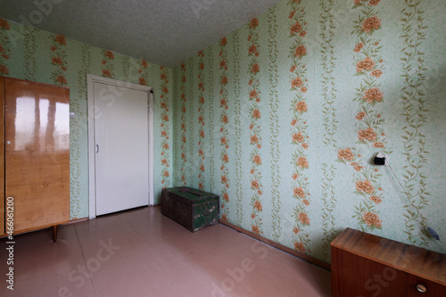 Example of Old Soviet Russian poor interior in Leningrad project House. Aged  sideboard, table, chairs, bed. Shabby floor. Tattered wallpaper on the wall. Apartment of pensioners. Selective focus.