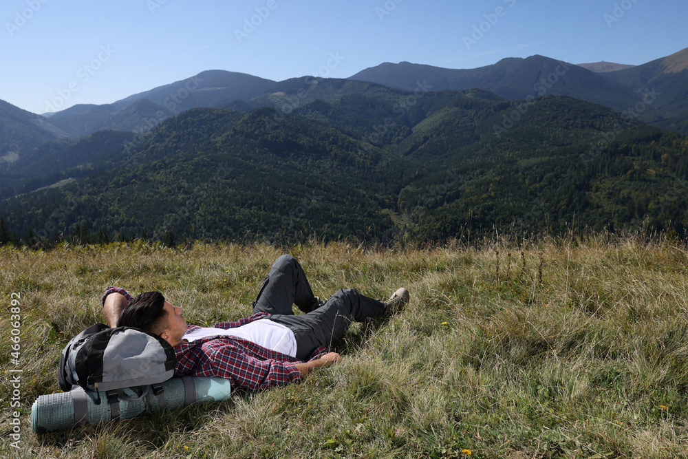 Tourist with backpack resting on ground in mountains Tourist with backpack resting on ground in mountains