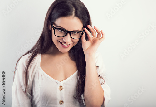 Beautiful natural smiling woman in modern glasses looking happy on blue background. Closeup