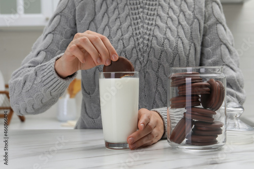 Φωτογραφία Woman dipping delicious choco pie into glass of milk at white marble table, clos
