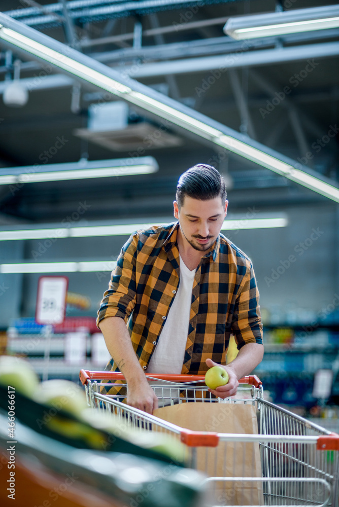 Young handsome man in a supermarket grocery shopping