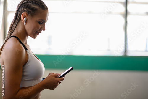 Woman using smartphone and airpods after finishing her training outside