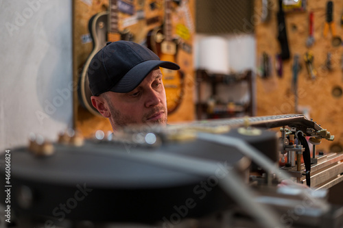 Guitar luthier fixing and repairing guitar in his guitar repair service shop