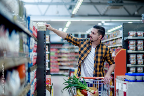 Young handsome man in a supermarket grocery shopping