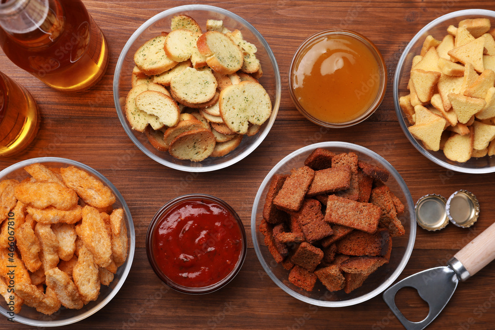 Different crispy rusks, beer and dip sauces on wooden table, flat lay Different crispy rusks, beer and dip sauces on wooden table, flat lay