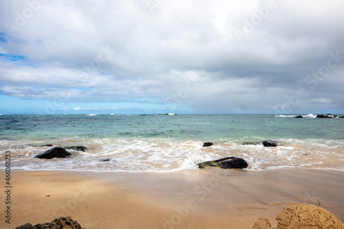 ocean, black rocks, waves and blue cloudy sky