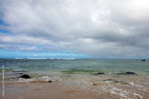 ocean, black rocks, waves and blue cloudy sky