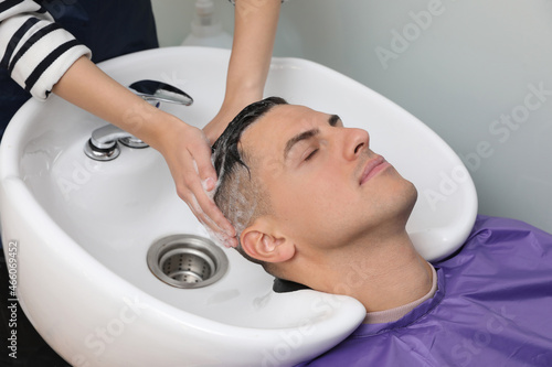 Professional hairdresser washing client's hair at sink, closeup