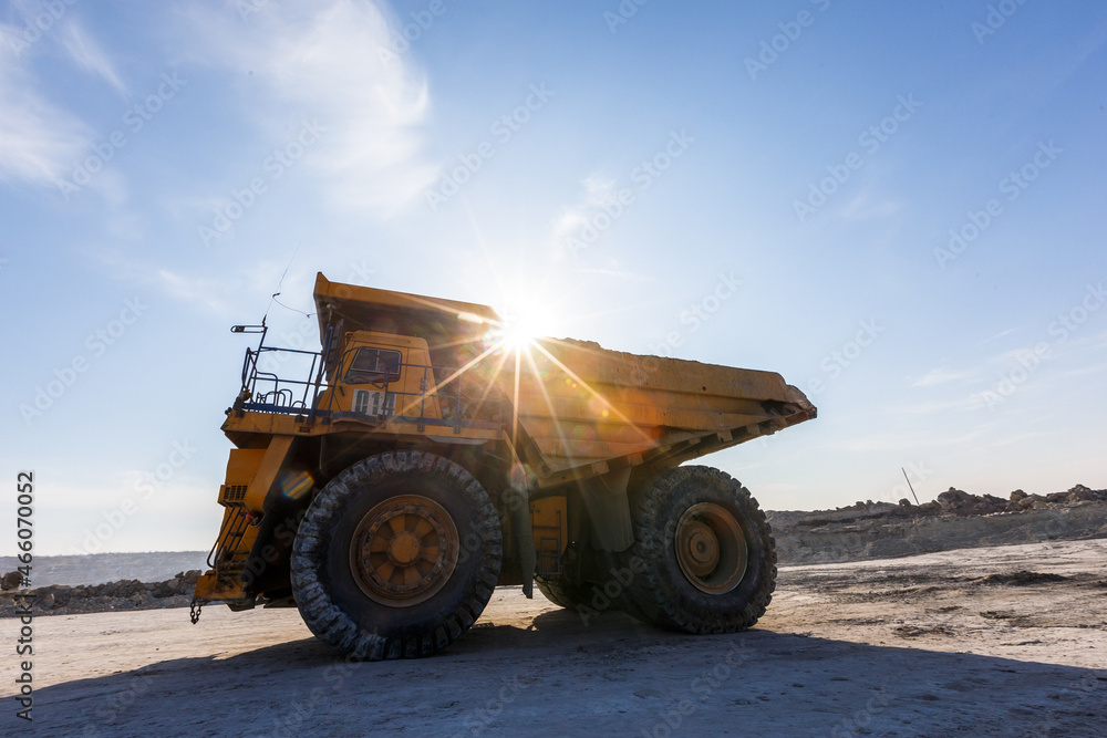 Industrial work in an open pit coal mine. A large yellow dump truck is carrying coal soil through the quarry. Open pit coal mining. Industrial work in an open pit coal mine. A large yellow dump truck is carrying coal soil through the quarry. Open pit coal mining.