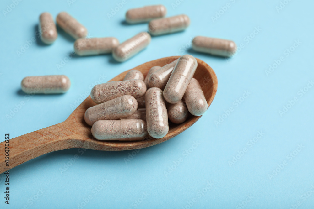 Gelatin capsules in spoon on light blue background Gelatin capsules in spoon on light blue background