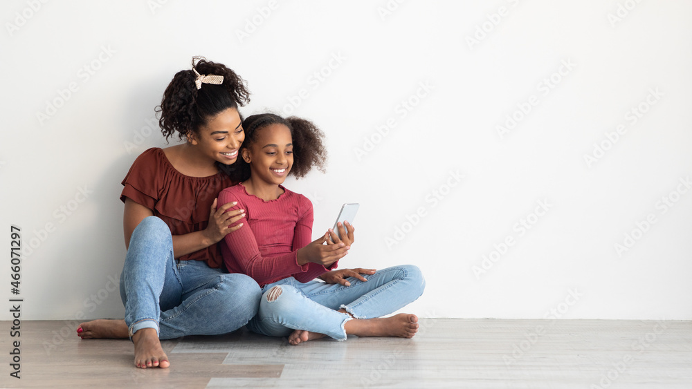 Beautiful black mother and daughter using mobile phone, panorama Beautiful black mother and daughter using mobile phone, panorama