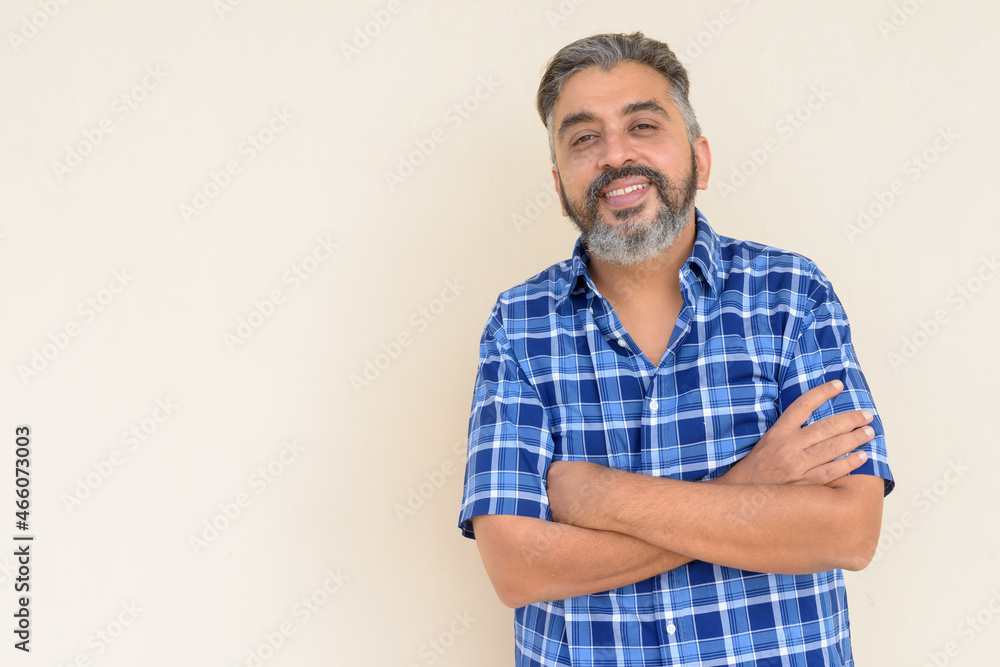 Portrait of bearded Indian businessman smiling against plain background Portrait of bearded Indian businessman smiling against plain background