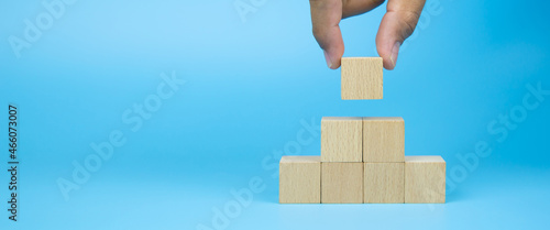 Close-up hand choose cube wooden block toy stack in pyramid without graphics for Business design concept and activity for children foundation practice skills and preschool learning. photo