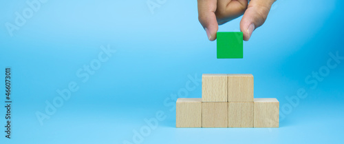 Close-up hand choose cube wooden block toy stack in pyramid without graphics for Business design concept and activity for children foundation practice skills and preschool learning. photo