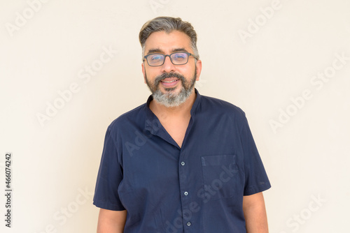 Portrait of bearded Indian businessman against plain background