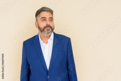 Portrait of bearded Indian businessman wearing suit against plain background