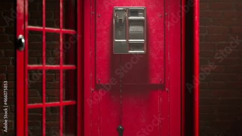 Black handset hanging in a red telephone box. Footage with a British phone booth photo