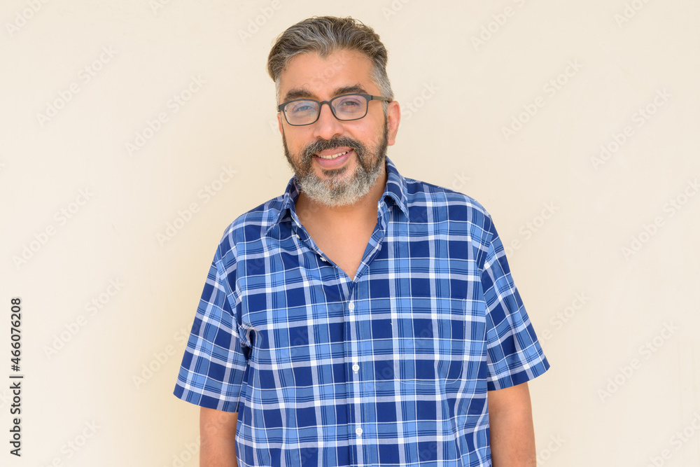 Portrait of bearded Indian businessman smiling against plain background Portrait of bearded Indian businessman smiling against plain background