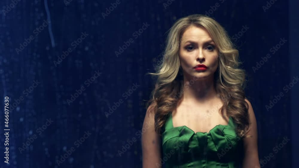 Beautiful sad girl in a green dress looks out the wet window during the rain at night. Beautiful sad girl in a green dress looks out the wet window during the rain at night.