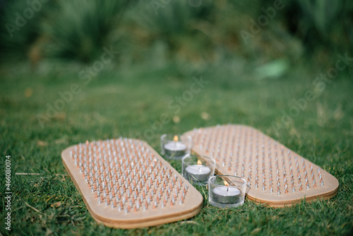Wooden board with metal nails for sadhu practice. Outdoor on green grass with candles. Yoga practice with sharp metal nails for forgiveness and overcome fears.
