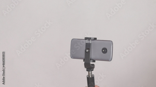 Cell phone mounted on a cell phone tripod, on white background.