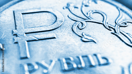 Translation: ruble. Fragment of the Russian 1 one ruble coin. The symbol or sign of the national currency of Russia. Blue tinted background or wallpaper about economy or finance. Macro photo