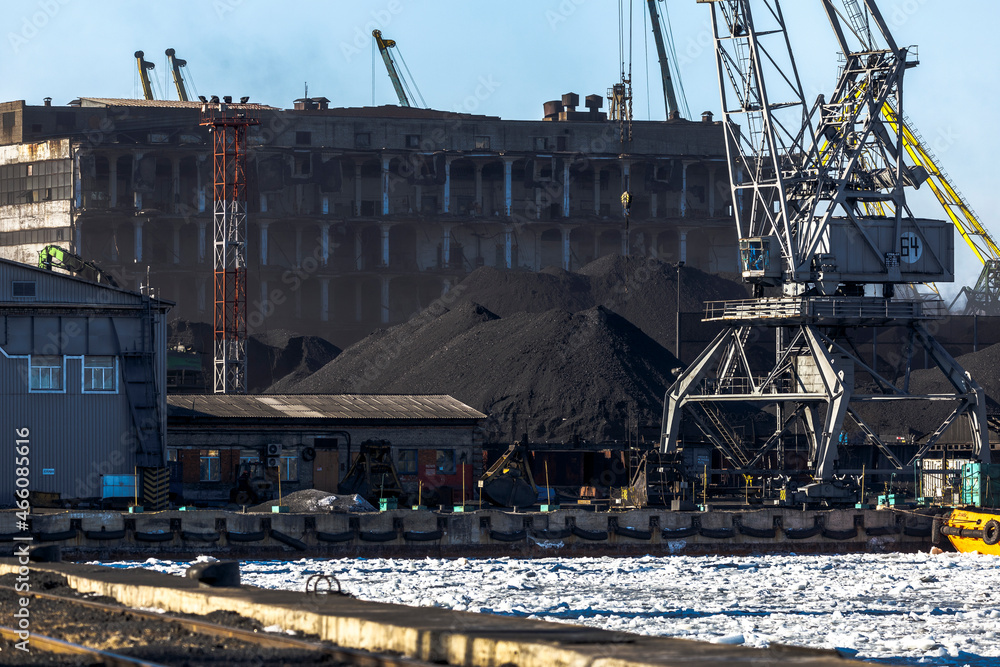 Industrial loading of coal into railway cars. Coal port of the city of Nakhodka. Large excavators are handling coal. Industrial loading of coal into railway cars. Coal port of the city of Nakhodka. Large excavators are handling coal.