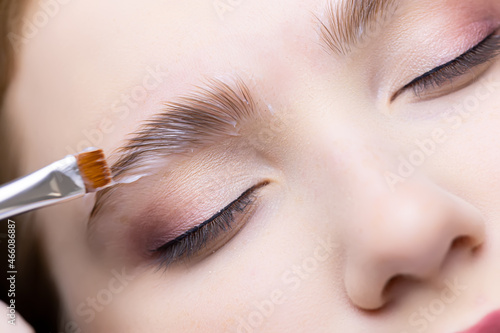 close-up of the eyebrows of the model on which the master applies laminating compositions with a brush
